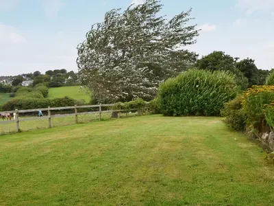 a large grass field with a fence and a tree at Gewans Farm Cottage in St Austell