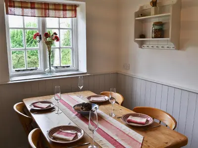 a table with chairs and a table with wine glasses at Gewans Farm Cottage in St Austell
