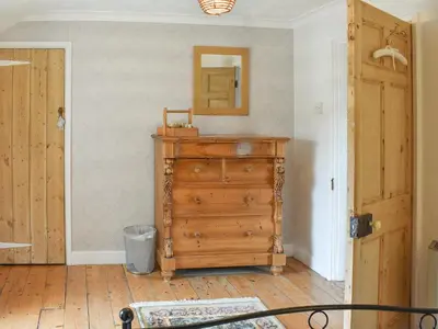a room with a wooden dresser and a mirror at Gewans Farm Cottage in St Austell