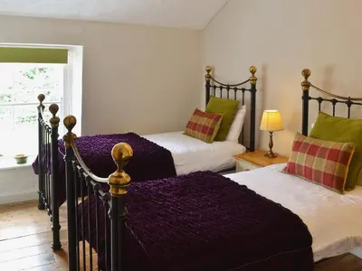 a bedroom with two beds and a window at Gewans Farm Cottage in St Austell