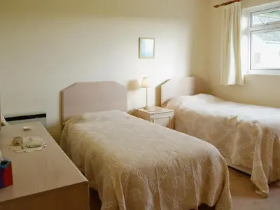 a bedroom with two beds and a table and a window at Goonlaze in St Austell