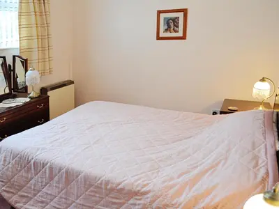 a bedroom with a white bed and a dresser at Goonlaze in St Austell