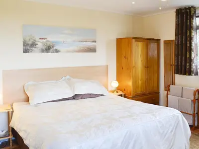 a bedroom with a large white bed and a chair at Scholten Lodge in Roche