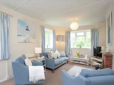 a living room with two blue couches and a tv at Sweet's Close in St Austell