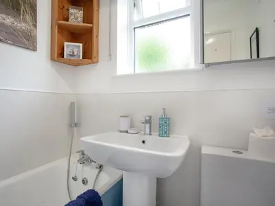 a white bathroom with a sink and a window at Sweet's Close in St Austell