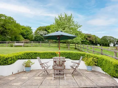 a table and chairs with an umbrella on a patio at Sweet's Close in St Austell