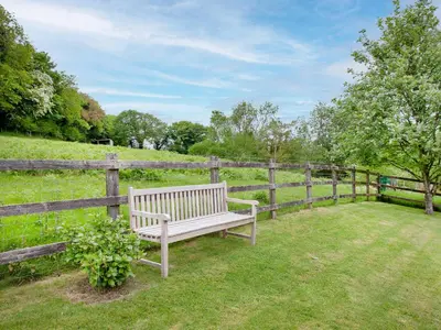 a wooden bench sitting in the grass next to a fence at Sweet's Close in St Austell