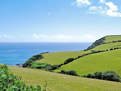 a green hillside with the ocean in the background at Sweet's Close in St Austell