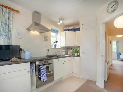 a kitchen with white cabinets and a stove top oven at Sweet's Close in St Austell