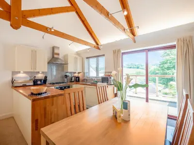 a kitchen with a wooden table and a large window at Villa Gallery - 27074 in Perranwell