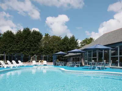 a swimming pool with chairs and umbrellas at Valley Gallery - 27075 in Perranwell
