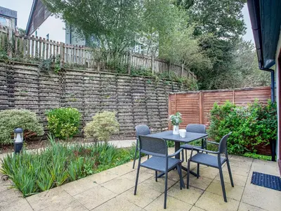 a patio with a table and chairs and a brick wall at Valley Gallery - 27075 in Perranwell