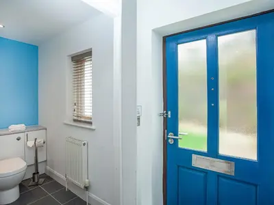 a bathroom with a blue door and a toilet at Villa Gallery-76 in Perranwell