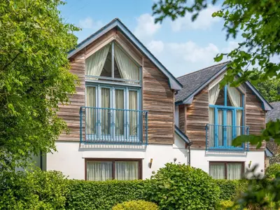 a house with wooden siding and blue windows at Haven -79 in Perranwell