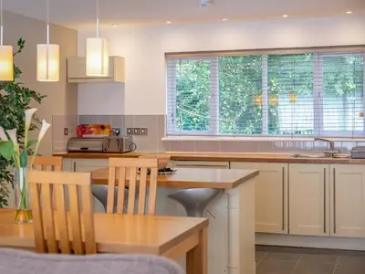 a kitchen with white cabinets and a wooden table at Haven -80 in Perranwell