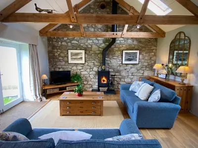 a living room with blue couches and a stone wall at The Stable in Crowan