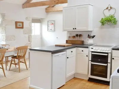 a kitchen with white cabinets and a black counter top at The Stable in Crowan