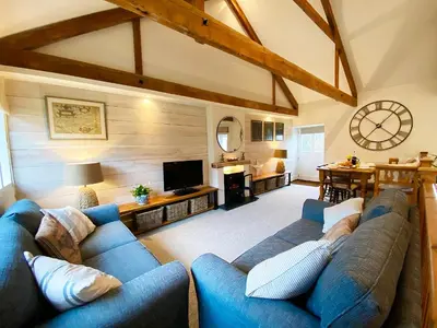 a living room with a blue couch and a tv at Swallows Barn in Crowan