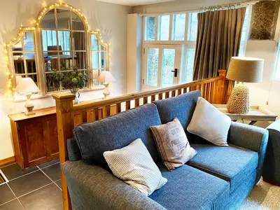 a living room with a blue couch with pillows at Swallows Barn in Crowan