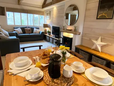 a living room with a table and a living room with a couch at Swallows Barn in Crowan