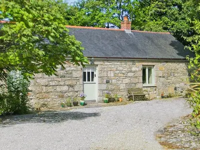 a stone house with a bench in front of it at The Long Barn in Crowan