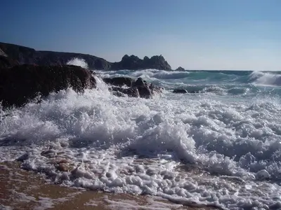 a group of waves crashing on the beach at The Long Barn in Crowan