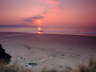 a sunset on a beach with the sun setting at The Long Barn in Crowan