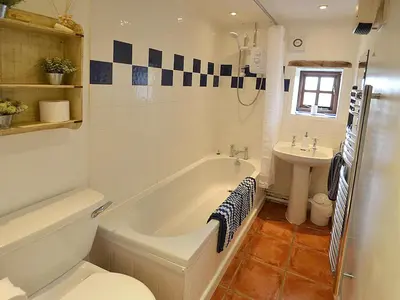 a bathroom with a tub and a toilet and a sink at The Long Barn in Crowan
