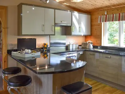 a kitchen with a counter and stools in it at Wheal Metal Lodge in Carleen