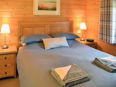 a bedroom with a bed with two lamps and two towels at Wheal Metal Lodge in Carleen