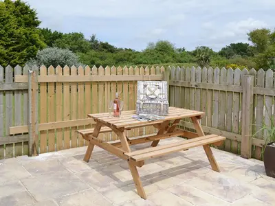 a wooden picnic table in front of a wooden fence at Beach Comber Cottage in Marazion