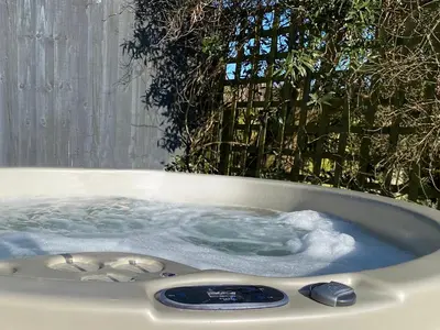 a jacuzzi tub with blue water in a garden at Beach Comber Cottage in Marazion