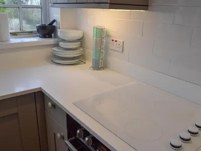 a kitchen counter with a stack of plates on it at Beach Comber Cottage in Marazion