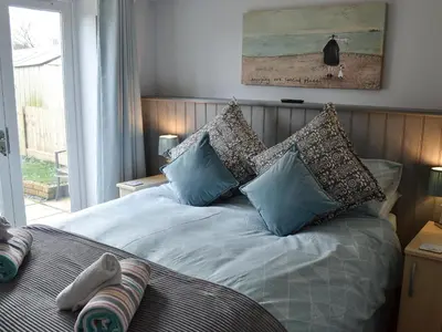 a bedroom with a bed with blue pillows and a window at Beach Comber Cottage in Marazion