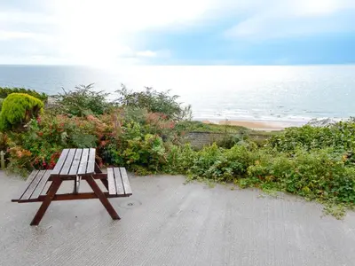 a wooden bench sitting on a path near the ocean at Suncroft in Praa Sands