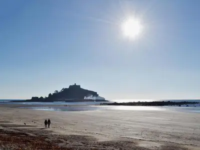 a couple of people walking on the beach at Thatch Cottage in Saint Hilary