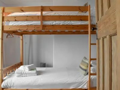 a bedroom with two bunk beds with white sheets at Hillside in Praa Sands