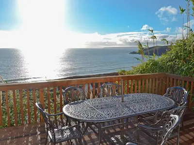 a table and chairs on a deck overlooking the ocean at Hillside in Praa Sands