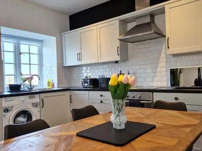 a kitchen with a wooden table with a vase of flowers at Very Spacious, Great location. Castle and Sea view in Marazion