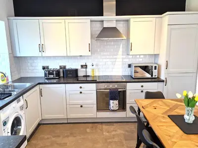 a kitchen with white cabinets and a wooden table at Very Spacious, Great location. Castle and Sea view in Marazion