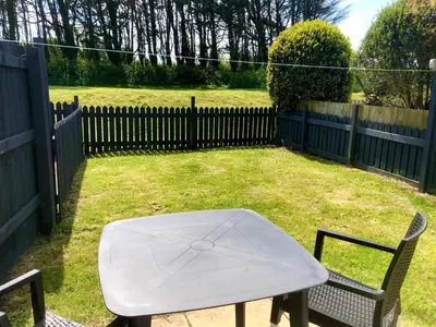 a white table and chairs in a yard with a fence at Very Spacious, Great location. Castle and Sea view in Marazion