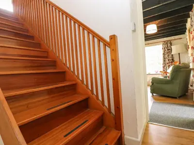 a wooden staircase in a house with a green chair at Byre in Camelford