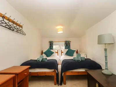 two twin beds in a room with a table at Byre in Camelford