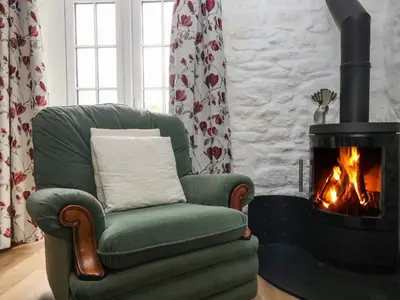 a green chair with a fireplace in a living room at Byre in Camelford