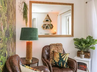 a living room with a chair and a mirror at Inny Brook Burrow in Camelford