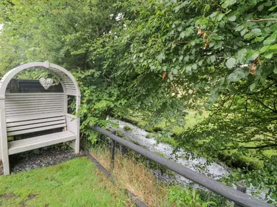 a wooden bench sitting next to a fence at Inny Brook Burrow in Camelford