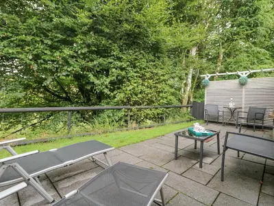 a patio with two chairs and a table and a fence at Inny Brook Burrow in Camelford