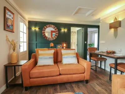 a living room with an orange couch and a table at Inny Brook Burrow in Camelford