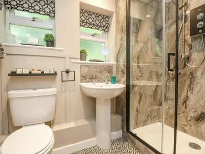 a bathroom with a shower and a toilet and a sink at Inny Brook Burrow in Camelford