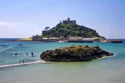 a small island in the ocean with people in the water at Great location very spacious. Sea and castle view in Marazion